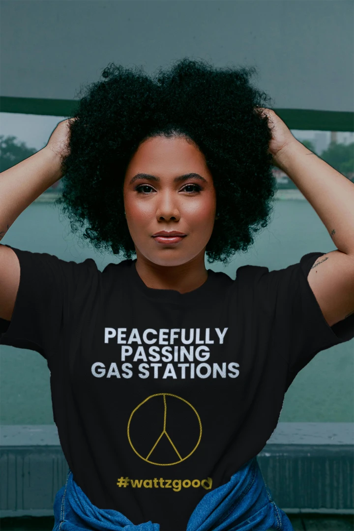 Woman wearing the black Wattz Good "Peacefully Passing Gas Stations" EV graphic tee with a yellow peace sign