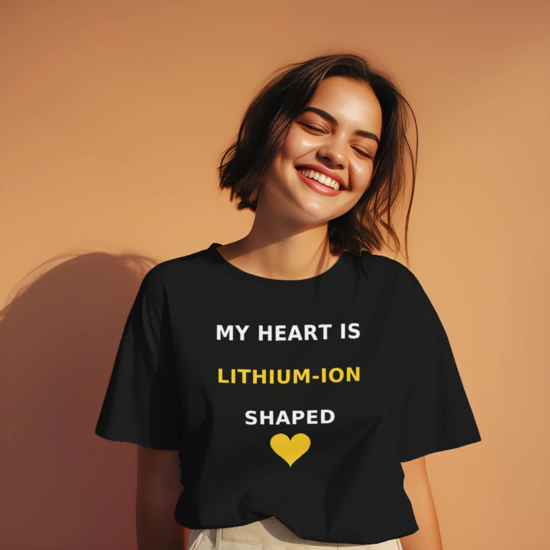Woman wearing the black Wattz Good "My Heart Is Lithium-Ion Shaped" EV graphic tee with a yellow heart