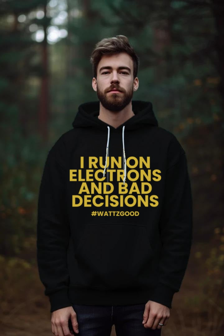 Man wearing the black I Run on Electrons and Bad Decisions Hoodie with yellow text and #WATTZGOOD, standing in a forest